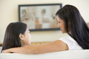 Woman and young girl in living room with flat screen television