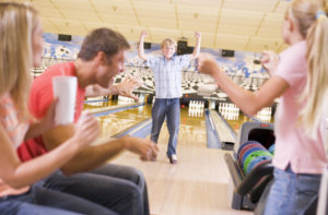 Family in bowling alley cheering and smiling