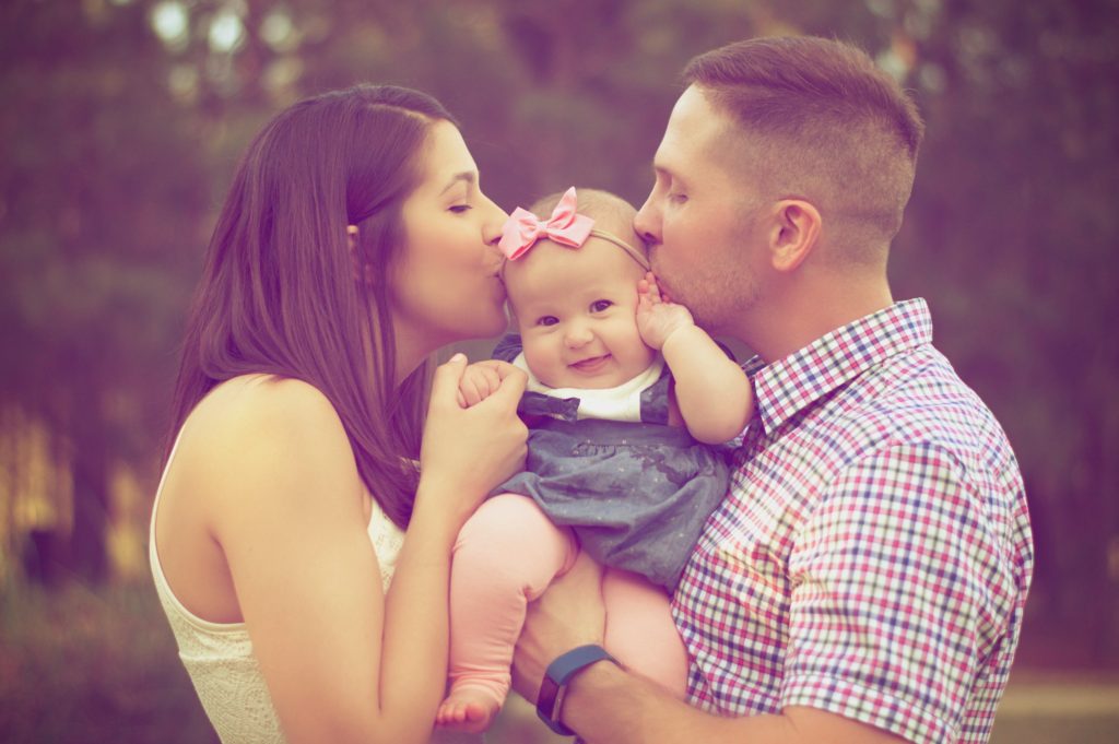 Young couple holding and kissing baby girl