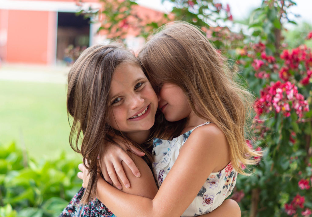 Two young girls smiling and hugging each other