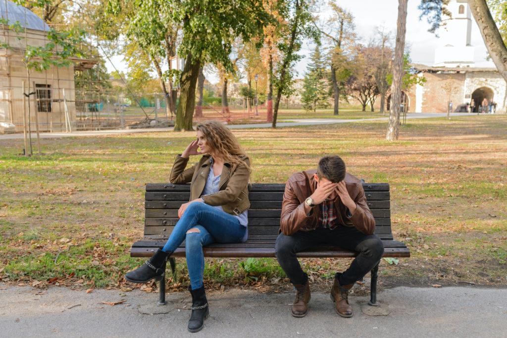 Young upset couple sitting on a bench