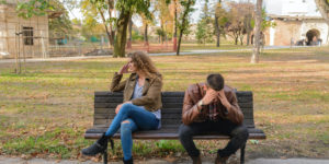 Young upset couple sitting on a bench